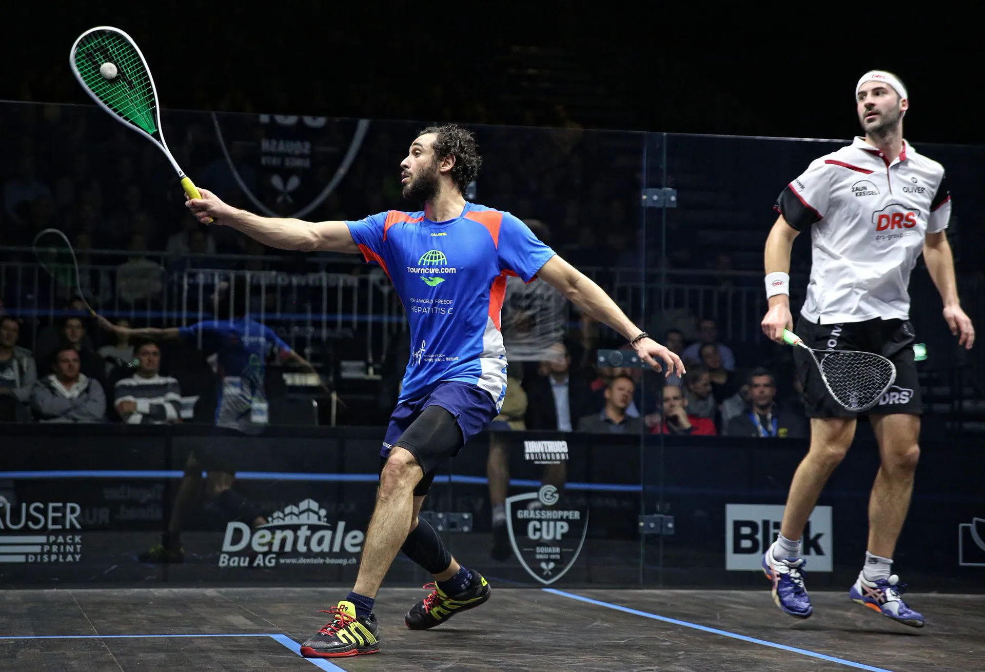 Ramy Ashour at full stretch in front of a packed glass court